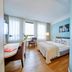 Flottwell Berlin Hotel guest room with bed, desk, and city-view windows in Berlin