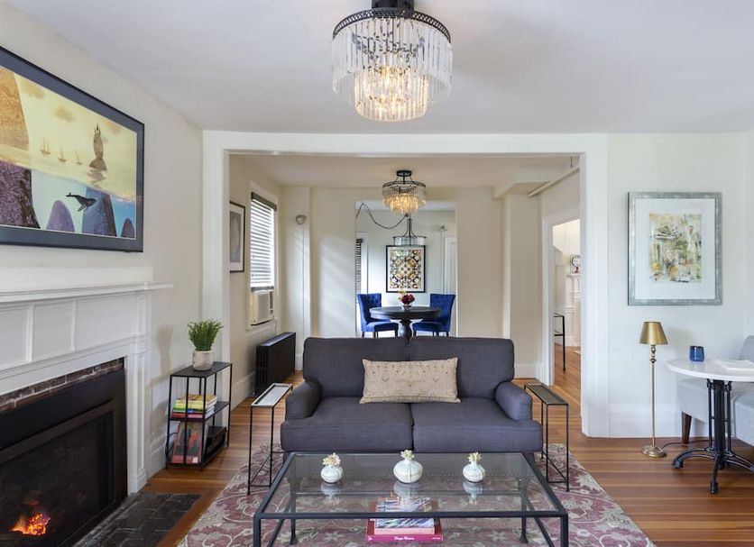 Chapter House Yarmouth living room with fireplace, sofa, glass coffee table and adjoining dining area