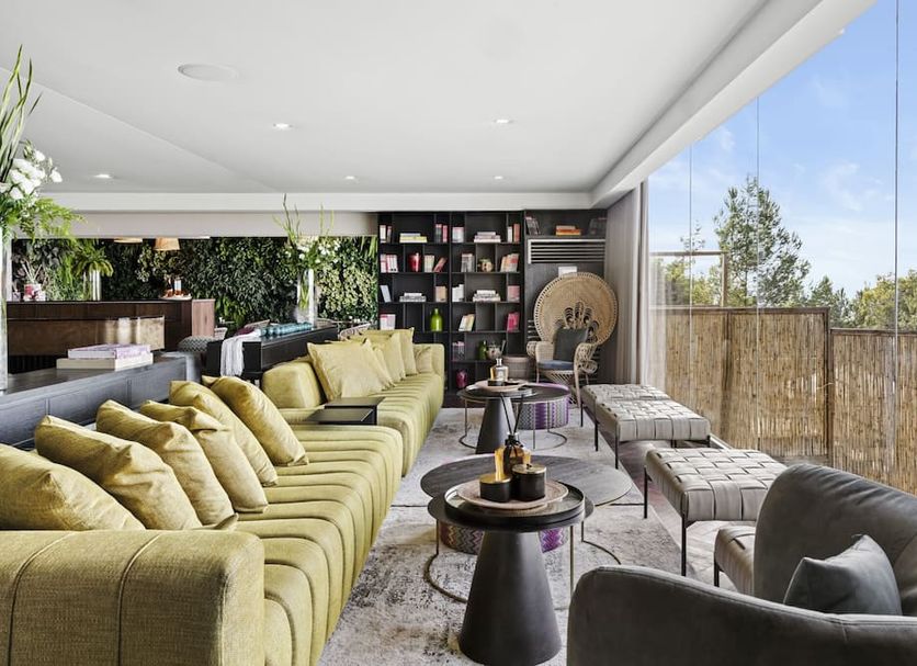 Gordonia Ma'ale Hahamisha lounge with green sofas and floor-to-ceiling windows overlooking trees