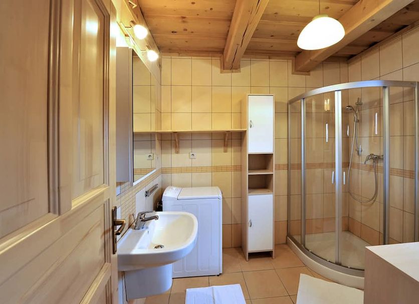 Sojka Resort Malatiny bathroom with walk-in shower, sink, washing machine and wood-beamed ceiling