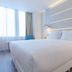 NH Monterrey La Fe guest room in Monterrey with a white bed, large window, and modern bedside tables