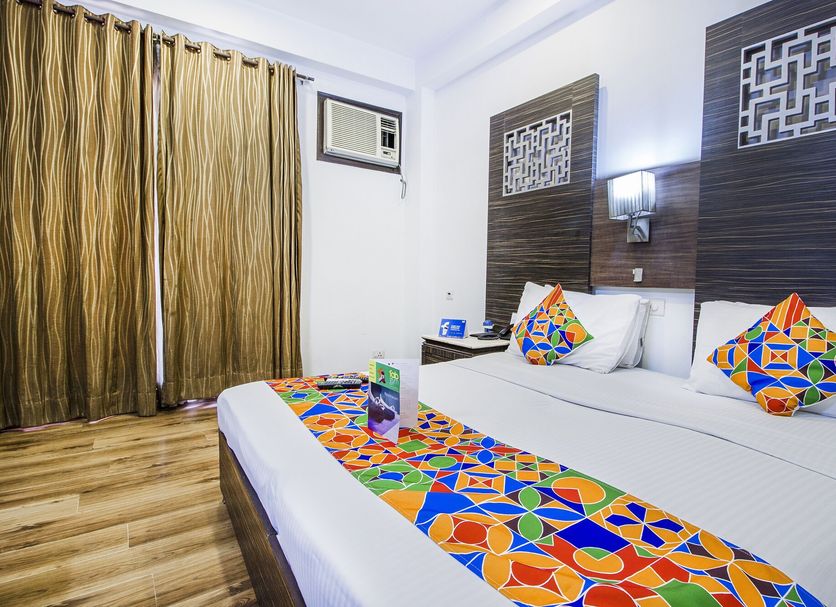 Hotel Sunstar Heights in New Delhi room with colorful geometric bed runner, pillows, and curtains