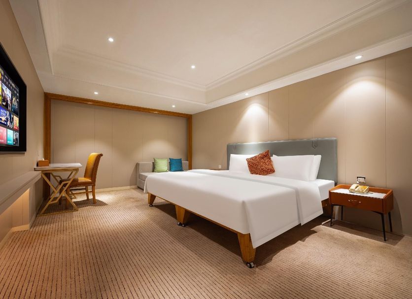 Wanhao International Hotel Benxi guest room with king bed, desk, TV, and neutral decor