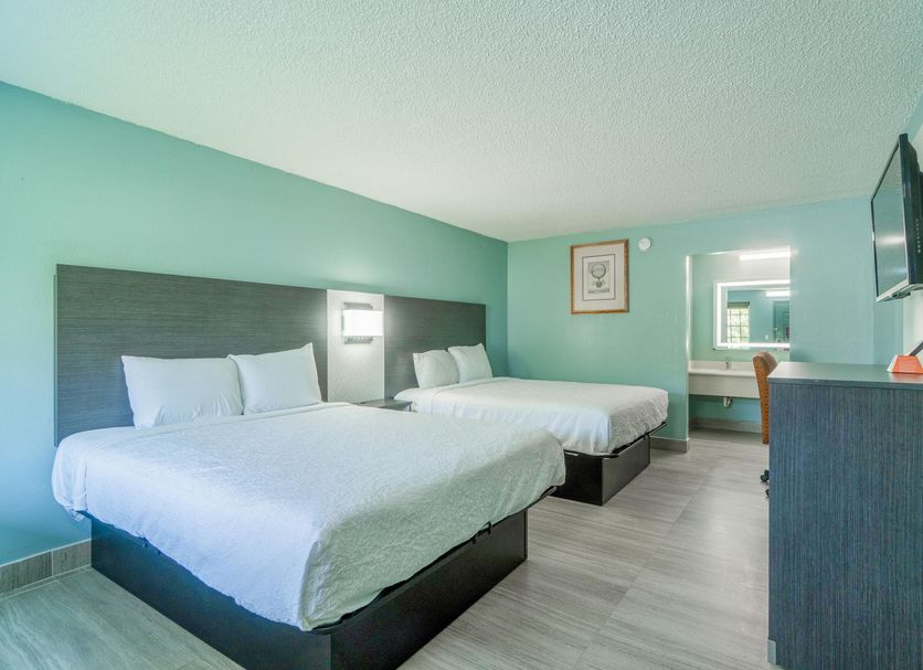 Lone Star Inn & Suites in Harlingen guest room with two beds, wall-mounted TV and vanity