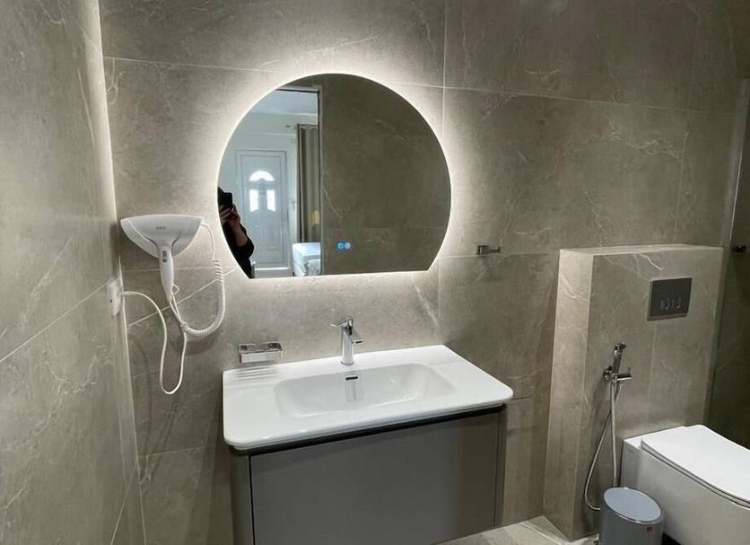 La Maroja View Hotel in Dhërmi bathroom with illuminated round mirror, sink, shower, and toilet