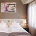 Empress Hotel Munich guest room with twin beds, bedside lamps and window curtains