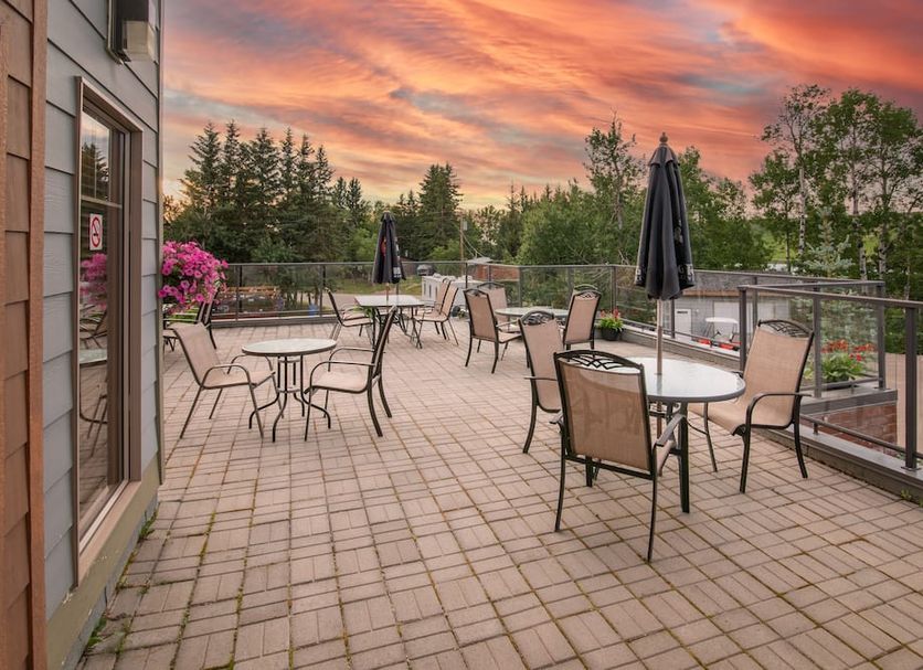 Elkwater Lake Lodge And Resort patio with tables and chairs overlooking trees at sunset in Elkwater