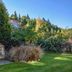 Shotover Lodge in Queenstown with a stone outdoor fireplace beside a lush garden and lawn