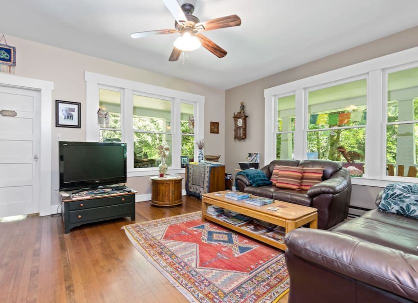 Mountain Meadows Inn & Chalet Suites in Ashford living room with leather sofas, TV, and large windows