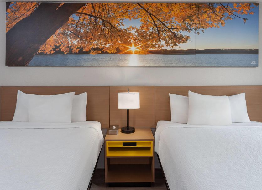 Days Inn by Wyndham Mason City guest room with two beds and a scenic sunset wall art
