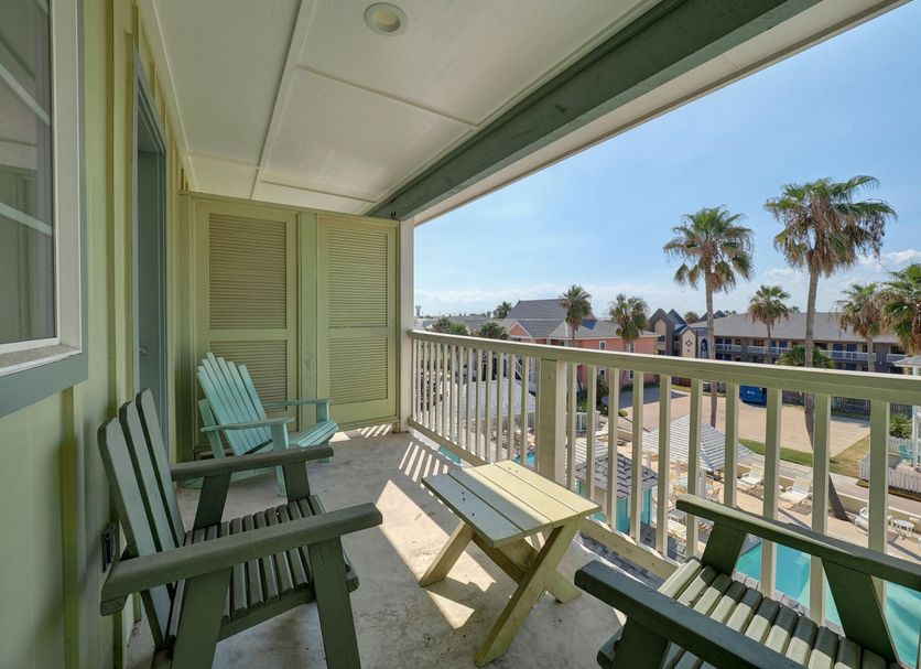 Seashell Village Resort Port Aransas balcony with chairs and view of palm trees and pool