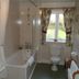 Manor Farm B&B bathroom in Marlborough with bathtub, sink, toilet and window with floral curtains