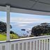 Lottin Point Motel in Hicks Bay with a covered porch overlooking the ocean and coastal hills