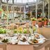 Bahia Del Duque in Adeje: elegant courtyard restaurant with table set amid lush potted plants and fountain