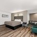 Quality Inn & Suites Biloxi - Ocean Springs guest room with king bed, desk nook and teal chair