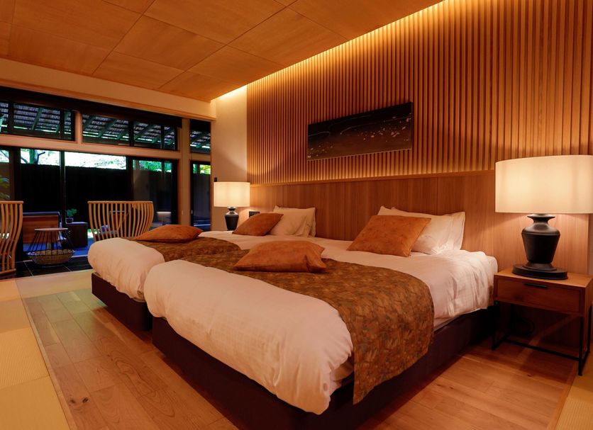 Sakahijiri gyokushoen in Izu: warm guest room with twin beds, wood-paneled walls and balcony seating