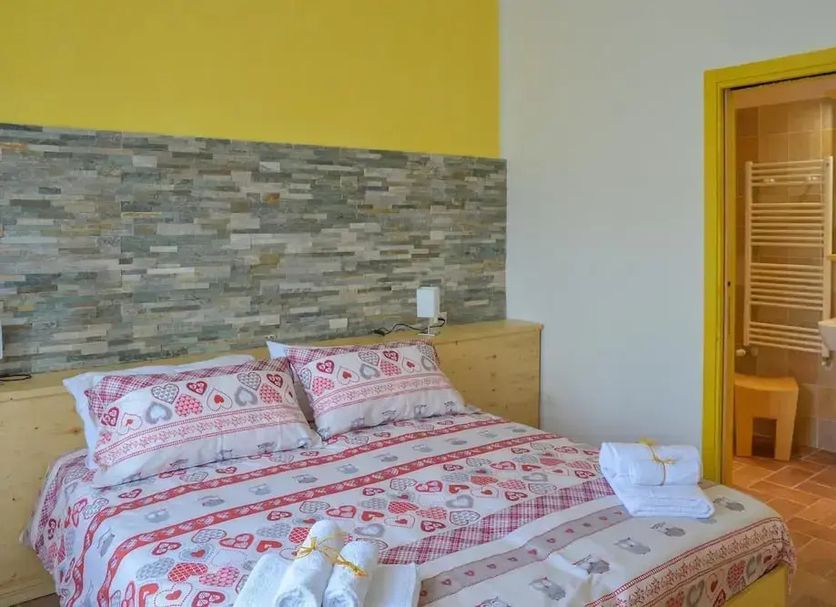 Al Riparo Affittacamere in Finale Ligure: double bed with patterned bedding and adjacent bathroom doorway