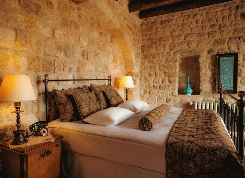 Yunak Evleri Cappadocia bedroom in Ürgüp with stone walls, lamps, and a neatly made bed