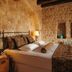 Yunak Evleri Cappadocia bedroom in Ürgüp with stone walls, lamps, and a neatly made bed