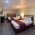 Best Inn & Suites Buena Park room with two beds, desk, wall-mounted TV and floor lamp