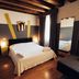 Ristolocanda Grani di Pepe in Flaibano bedroom with exposed beams, bed, mirror and dark curtains