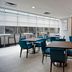 Hampton Inn New York-JFK in Queens with a modern dining area and blue chairs by large windows