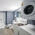 Nesuto The Entrance Apartments bathroom with shower over tub, sink, toilet and stacked washer dryer
