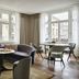 Rosewood Vienna in Vienna lounge with curved sofa, round tables and large windows overlooking the street.