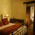 Las Iglesias Antigua guest room with wrought-iron bed, red pillows, lamp, and doorway to bathroom