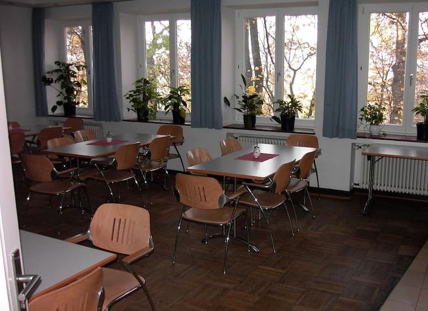 Jugendherberge Aachen dining room with tables, chairs and windows overlooking trees