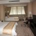 Xiang Ming Holiday Hotel in Huangshan guest room with two beds, desk, chairs, TV and window curtains
