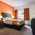 Motel 6 Surrey BC guest room with orange accent wall, bed, window, and TV in Surrey