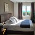 Hpc Suites Cassis room with king bed, window sea view, and potted plant