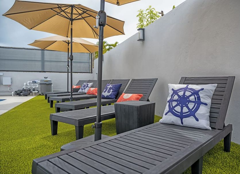 Casa Toñita in Levittown: rooftop lounge chairs with umbrellas and ship-wheel pillows on artificial grass