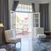 Napper By Rottenberg in Havana room with balcony doors open to a city view and two chairs