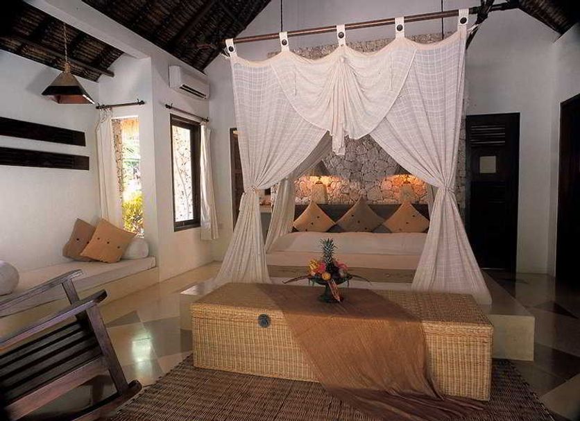 Nusa Lembongan Resort in Nusa Penida, airy suite with canopy bed and woven coffee table