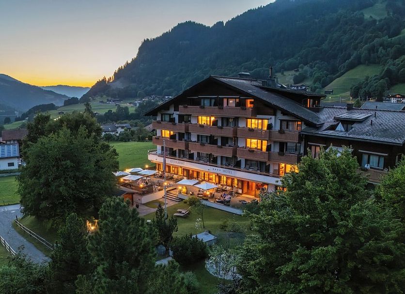 Sunstar Hotel Klosters in Klosters-Serneus at dusk, with lit balconies and mountain valley views