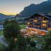 Sunstar Hotel Klosters in Klosters-Serneus at dusk, with lit balconies and mountain valley views