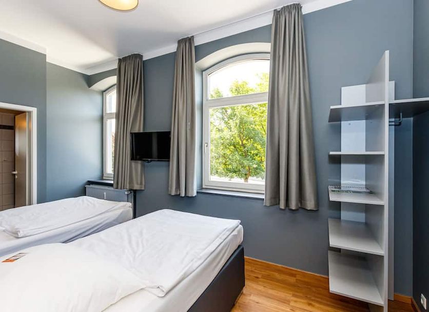 Sehnder Hof in Sehnde guest room with twin beds, wall-mounted TV, window, and shelving unit