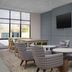 Hampton Inn Crossville lounge with patterned chairs, round tables and wall-mounted TV