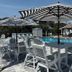 Ocean Eleven Suites in New Smyrna Beach poolside patio with striped umbrellas, tables and lounge chairs