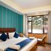 Hotel Woodrina in Shimla guest room with king bed, wall-mounted TV and window seat overlooking trees
