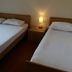 Residence Valbella in Bibione: guest room with two beds, bedside lamp, and simple wooden furniture