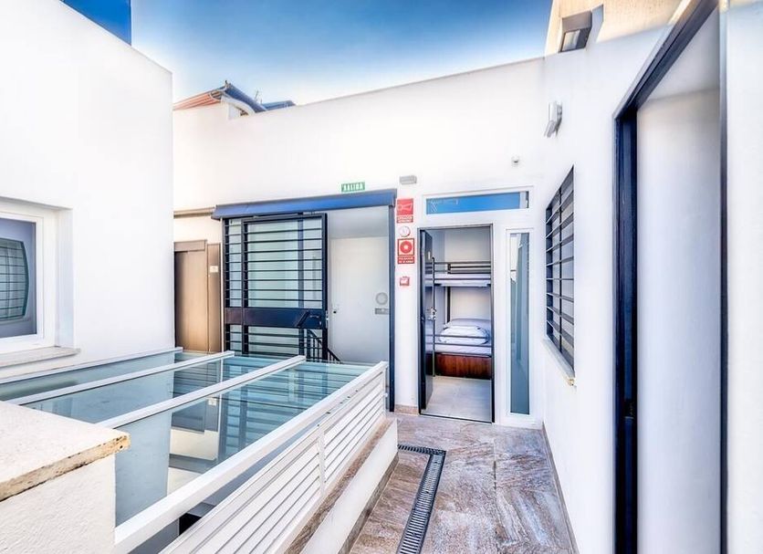 Hostel A2C in Seville courtyard with glass floor feature and open room doorway