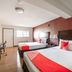 OYO Hotel Mcallen Airport South guest room with two beds, red accent wall, desk and TV in McAllen