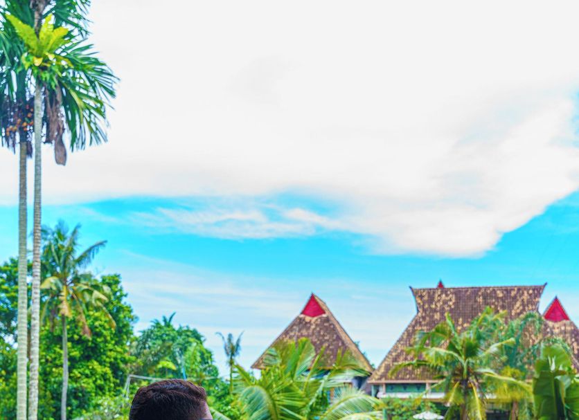 Hotel Deli River and Restaurant Omlandia in Medan, man on balcony overlooking tropical garden and huts