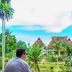 Hotel Deli River and Restaurant Omlandia in Medan, man on balcony overlooking tropical garden and huts