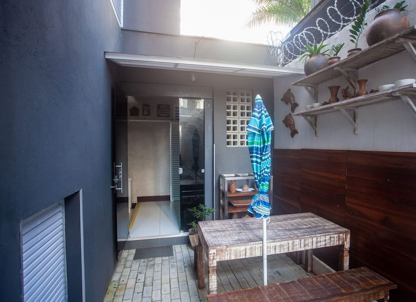 Economy Apart in Natal outdoor patio with wooden bench, table, wall shelves and hanging plants