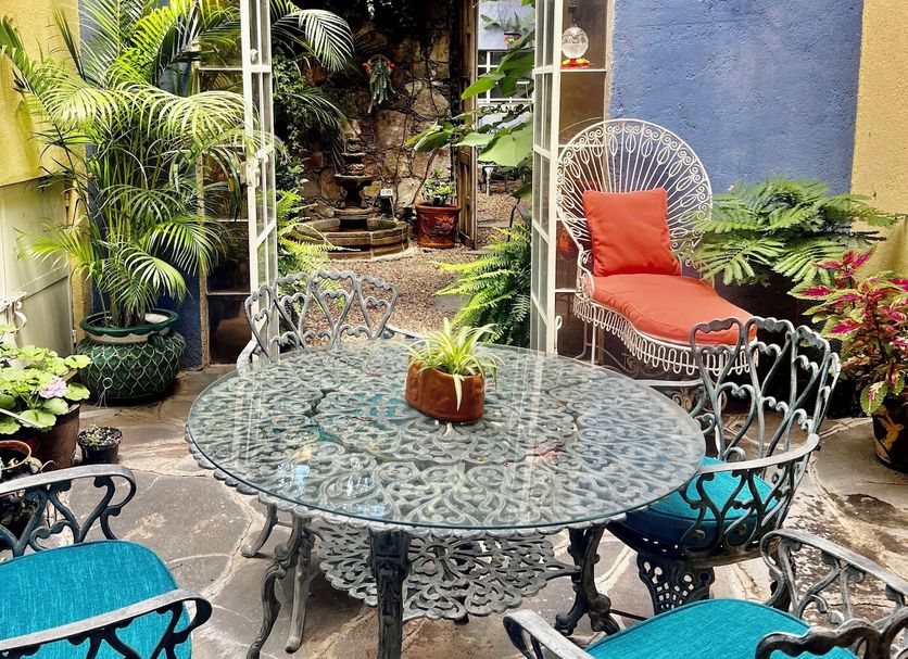 Boutique Hotel Casa Camellia patio in San Miguel de Allende with lush plants, mosaic table and wicker chairs