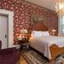Munro House B And B in Jonesville: ornate guest room with four-poster bed, chandelier, fireplace and floral wallpaper